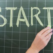 Start concept, woman’s hand with chalk writing the word start on a blackboard